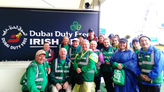 Group of volunteers standing beside the Dubai Duty Free Irish Open sign