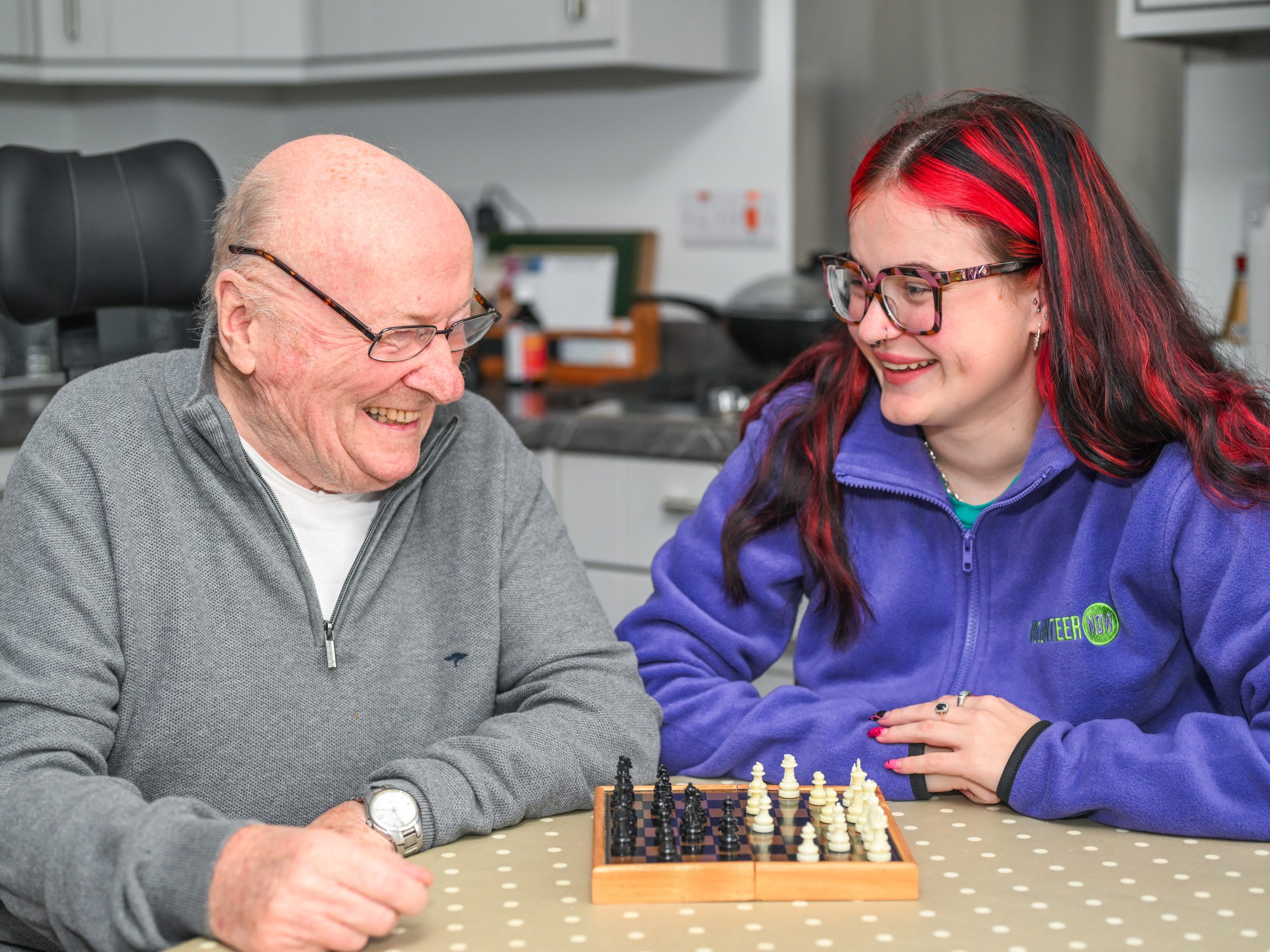 Volunteer Now befriender Amy, playing chess with an older man, Mike. Both are smiling so we're not sure who is winning!