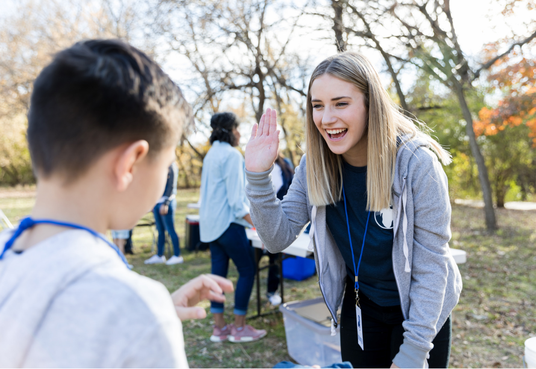A smiling youth volunteer high-fives a child