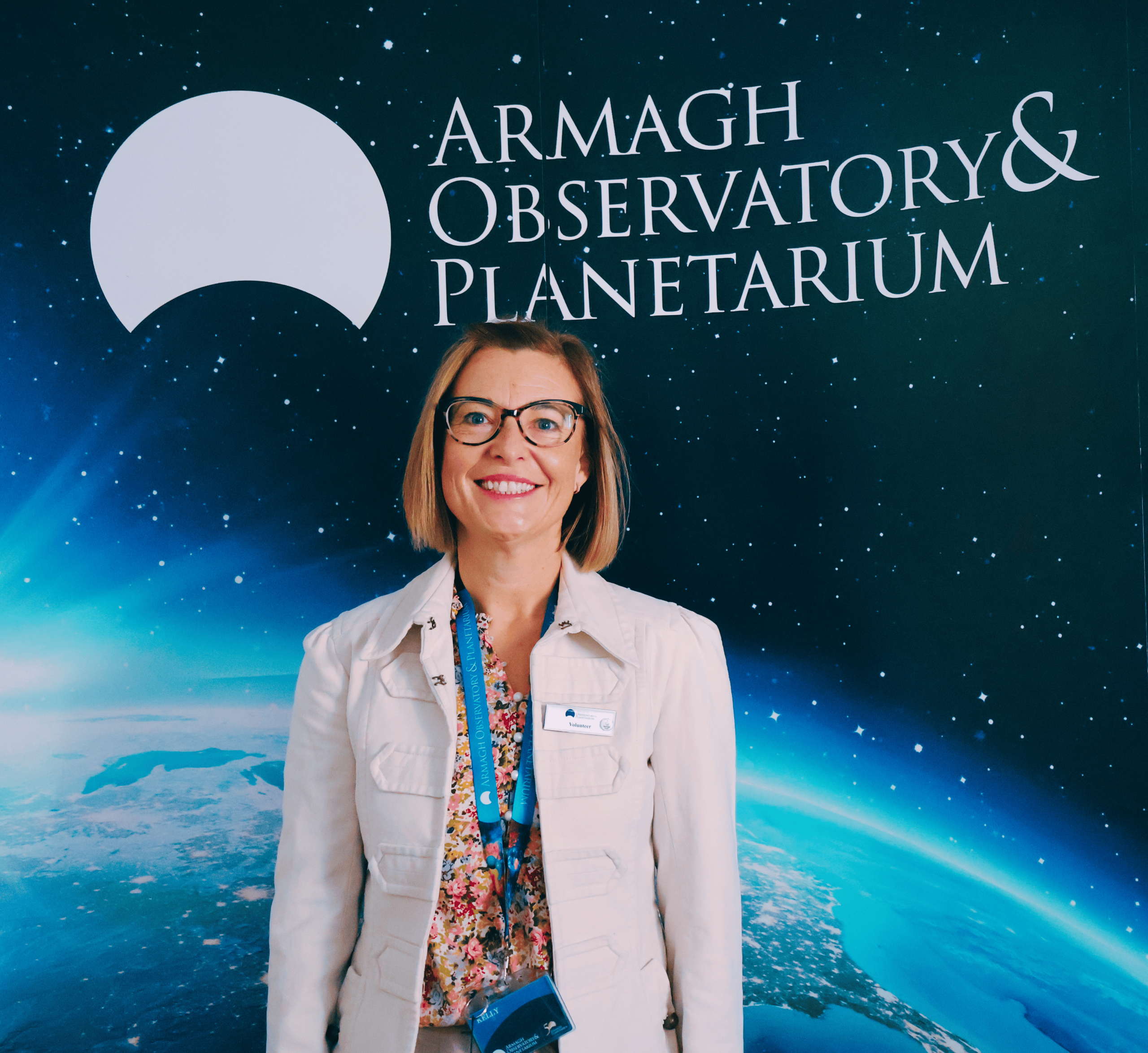 Kelly McGloin, Volunteer Co-Ordinator at AOP stands in front of an image of the earth and moon